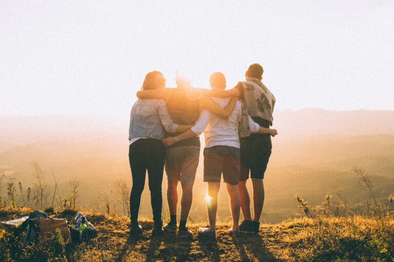 four people hugging in front of beautiful view