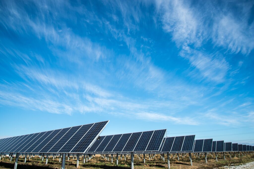 Solar panels in a field with large blue skies
