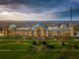 London, England - Aerial panoramic view of Alexandra Palace in Alexandra Park with iconic red double-decker bus and dramatic clouds behind