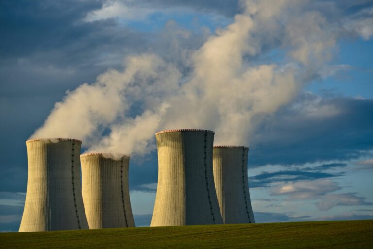 image of nuclear power plants in countryside in use with smoke coming out of them