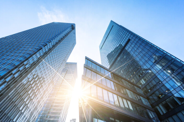 large office buildings in a city on a sunny day representing big corporations reaching net-zero