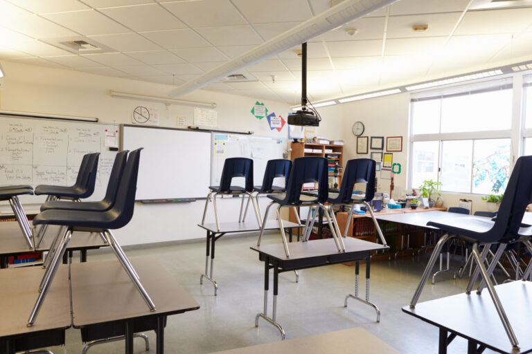 Empty classroom with chairs on tables representing How Schools Can Improve Energy Efficiency Over Summer
