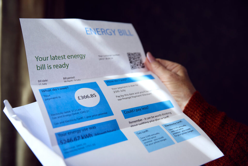 woman holding white and blue a4 energy bill with charges on including standing charge and dates