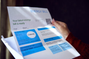 woman holding white and blue a4 energy bill with charges on including standing charge and dates