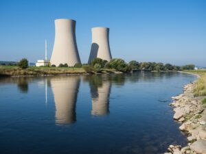 a body of water with two cooling towers in the background representing the nuclear rab levy