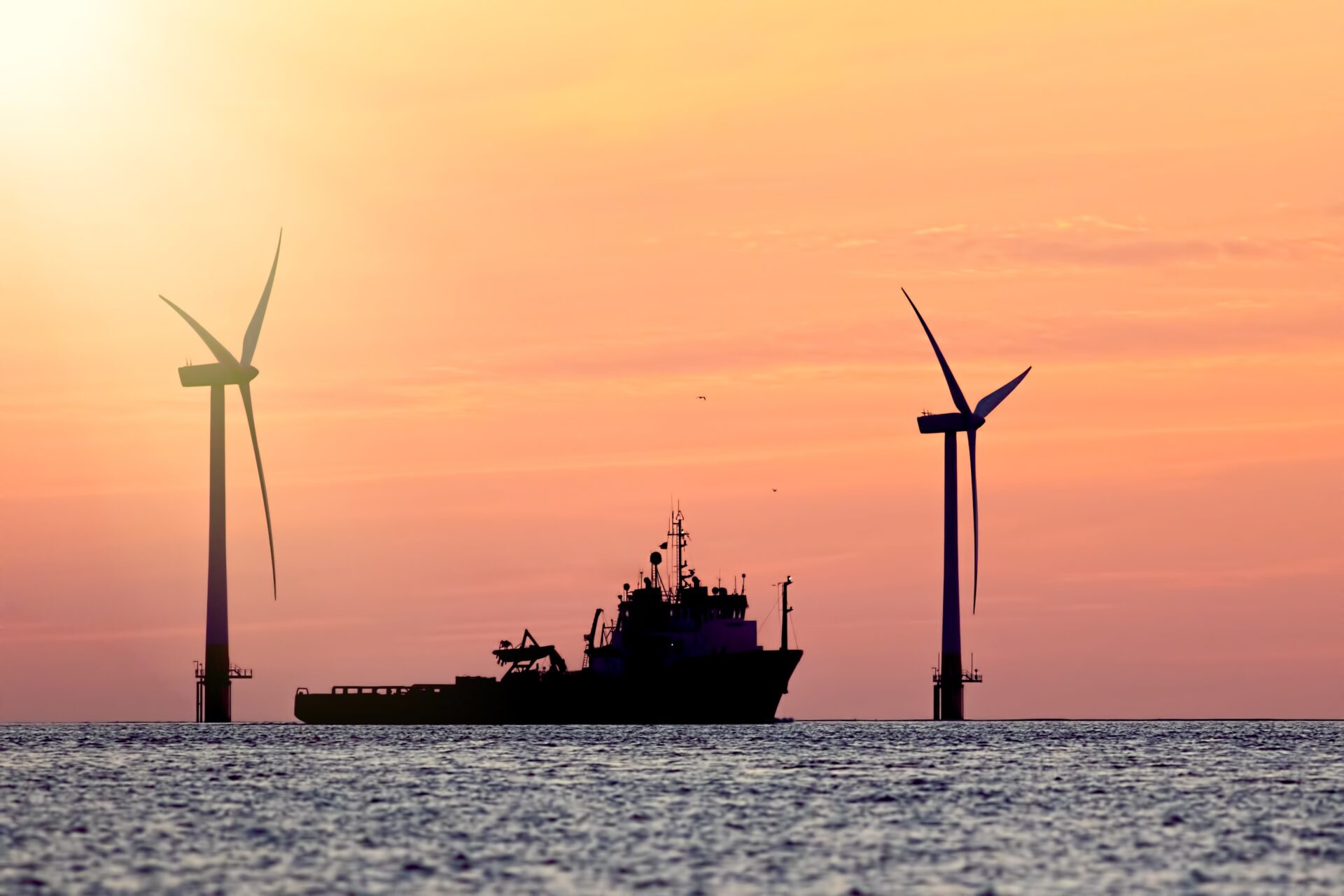 Ship near offshore wind turbines at sunset representing clean energy investment