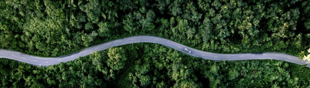 aerial view of car on road winding through trees representing innovation zero