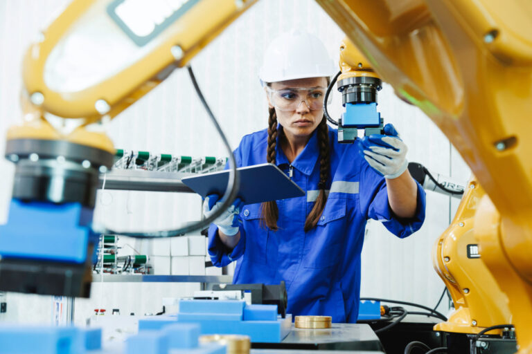manufacturing engineer in factory with robot arm representing high energy prices