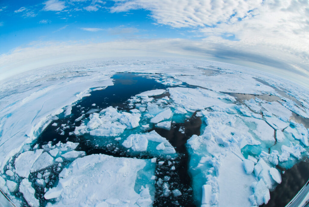 Arctic Ocean sea ice breaking up under blue sky, showing impacts of global warming and climate change