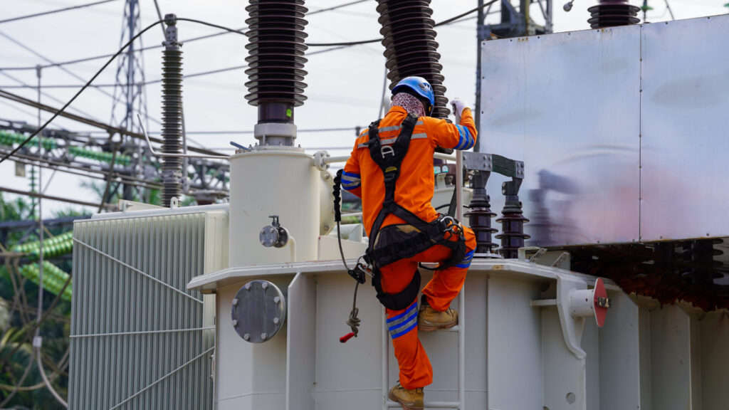 Electrical technician climbing transformer during maintenance work representing great british grid