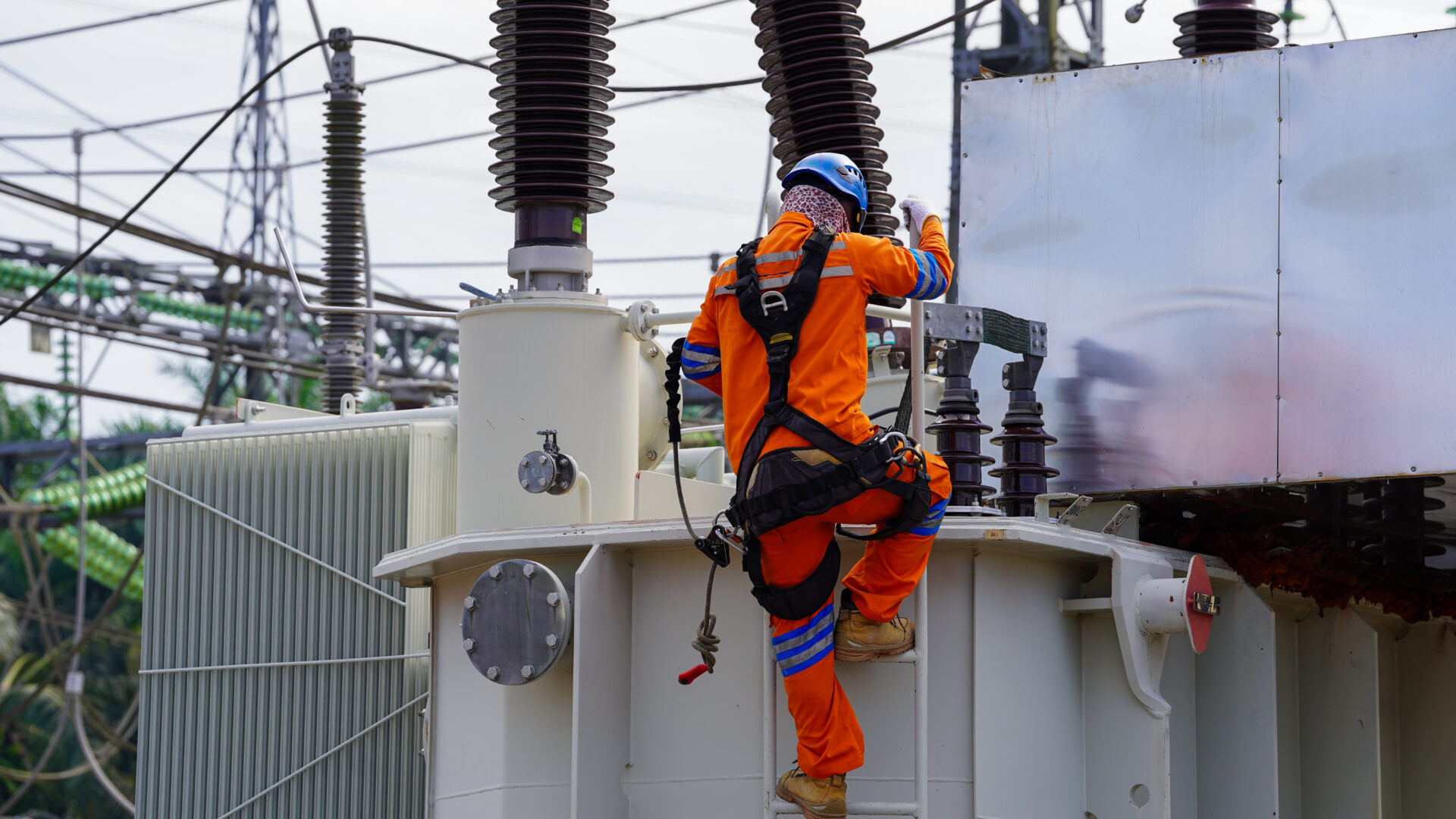 Electrical technician climbing transformer during maintenance work representing great british grid